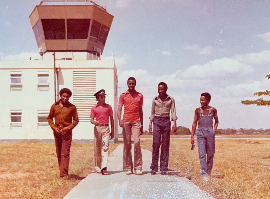 Five young people walking in front of an air control tower