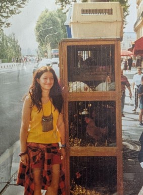 Young woman next to cages with bunnies and rabbits on a street.