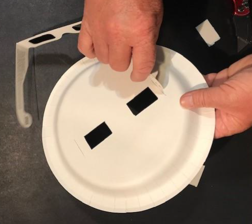 Image showing hands putting the arms of glasses through a hole on the side of the plate.