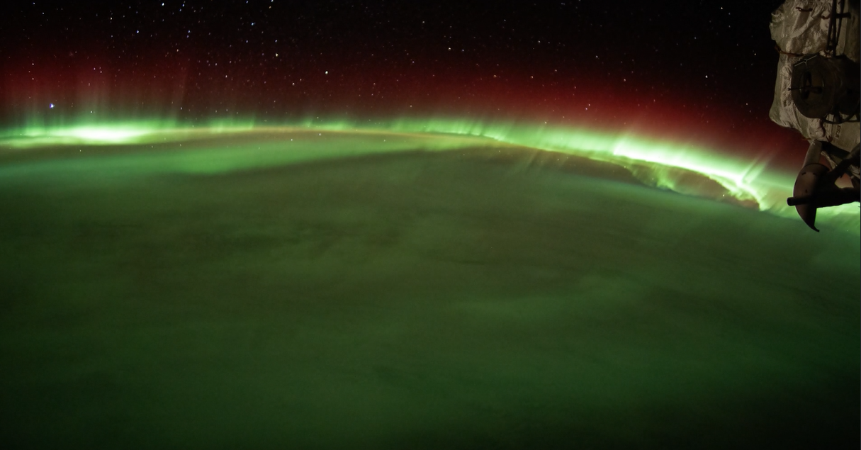 An image of the aurora australis as seen from the International Space Station. Green and red aurora are visible over the Earth.