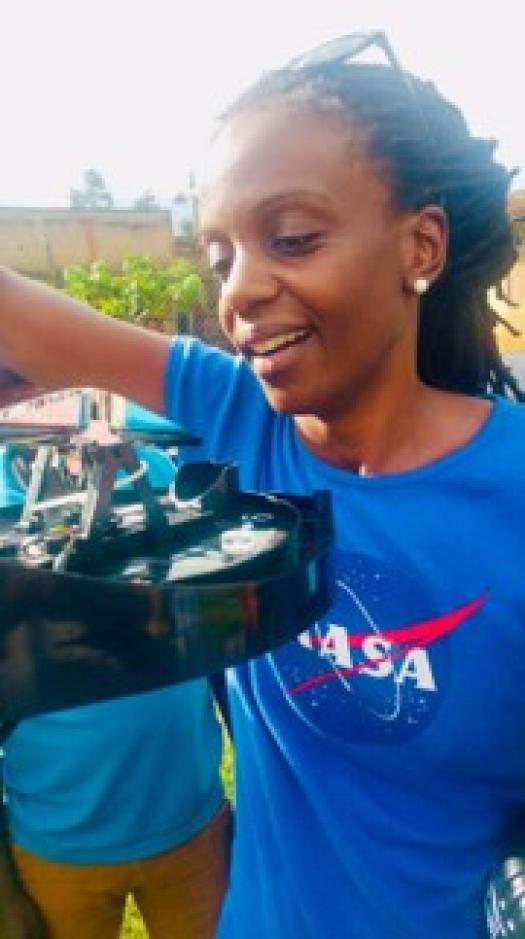 Catherine Nakalembe outdoors, wearing a NASA shirt